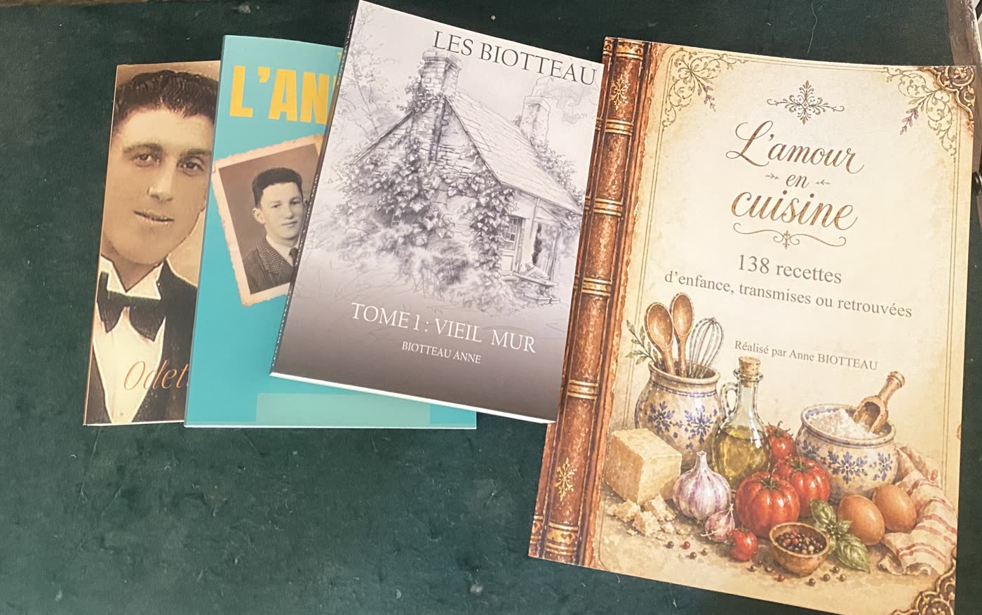 Quatre livres imprimés posés sur le secrétaire : Odette et Marcel, L'année 53, Vieil Mur et L'amour en cuisine